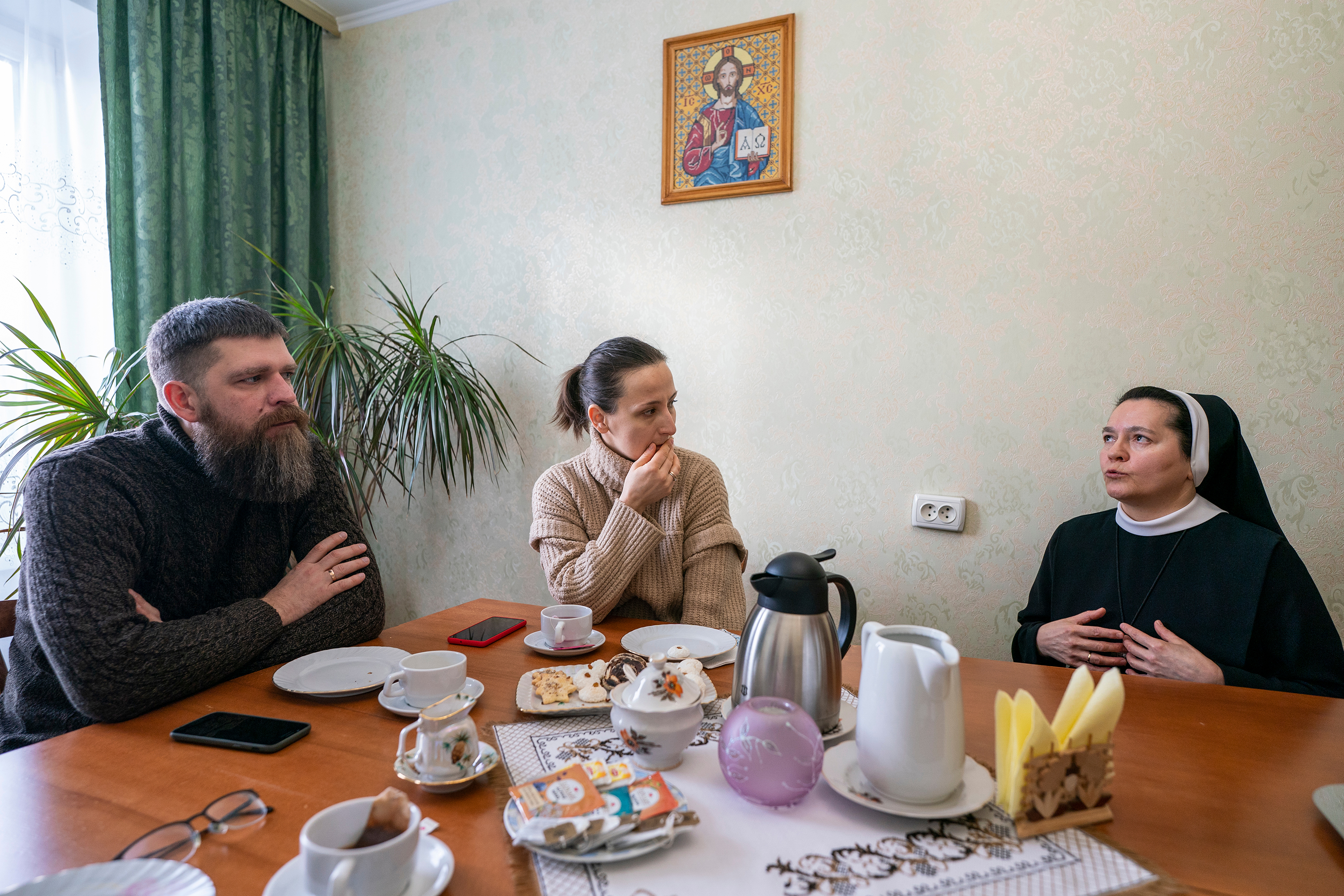 Translator Iryna Chernikova, center, and her husband, Stas Nepokrytyi, left, sit with Sr. Yanuariya Isyk, a member of the Sisters of the Order of St. Basil the Great whose ministry is based in the capital of Kyiv, here in the small monastery apartment shared with two other sisters. (GSR photo/Gregg Brekke)