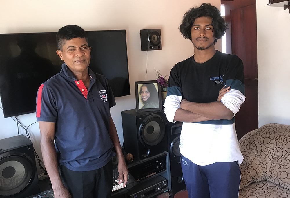 Priyantha Jayakodi, left, and his only son Hasaru Shenal stand before a photo of his wife, who was killed in the 2019 Easter bombing. (Thomas Scaria)