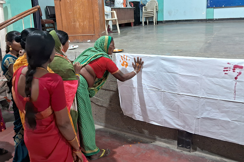 As the women arrive for the celebration of International Women's Day, they each add color to a white cloth, to imprint their contribution to the world. (Courtesy of Dorothy Fernandes)