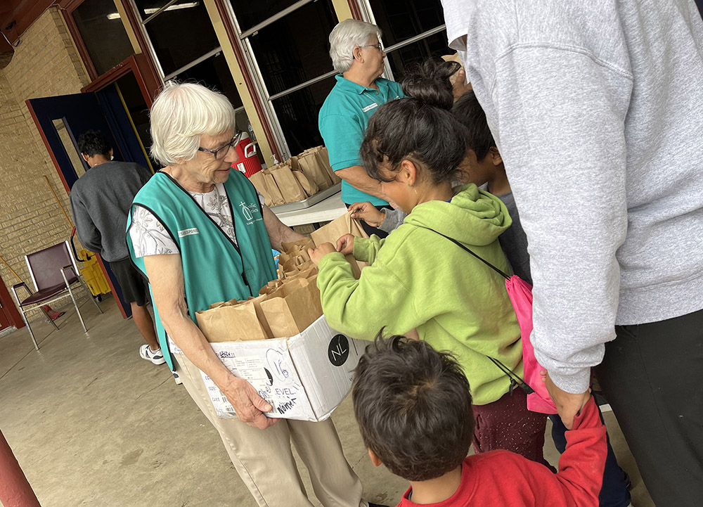 Notre Dame Sr. Roseanna Mellert and others hand out food to migrants at La Frontera's annex in Laredo, Texas. (Luis Donaldo Gonzalez)