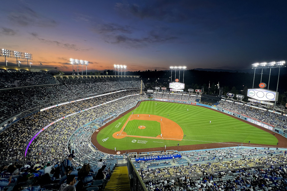 A baseball stadium is lit up at night as the sun slips below the horizon