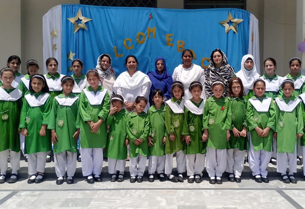 Presentation Sisters are pictured May 24 with students who survived a gun attack May 16 at Sangota Public School in Swat Valley, Pakistan. Classes resumed May 24 when the students recited prayer in the morning assembly. A sign behind them reads "Welcome back." (Courtesy of Sr. Teresa Younas)