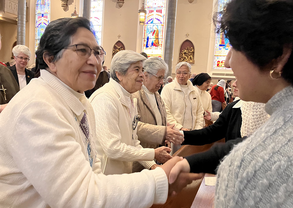 Sr. Rosa Cruz of the Guadalupan Missionaries of the Holy Spirit gives the sign of peace to Leslie Bocanegra, a young woman invited to attend the Mass to celebrate the World Day of Consecrated Life at St. Paul's Cathedral in Birmingham, Alabama. (Courtesy of Maria Elena Méndez Ochoa)