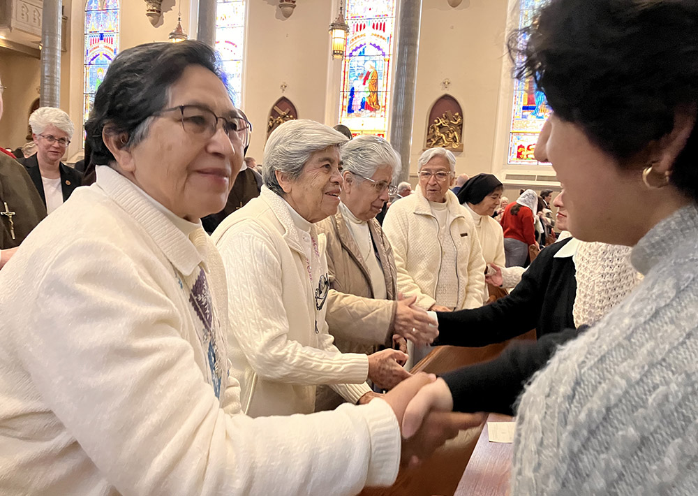 La Hna. Rosa Cruz, MGSpS, le da la paz a Leslie Bocanegra, joven invitada a celebrar la Misa del Dia Mundial de la Vida Consagrada en la Catedral de San Pablo, Birmingham, AL.