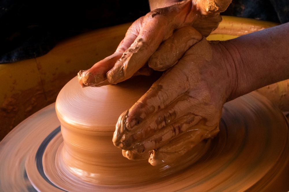 hands molding clay on a potters wheel