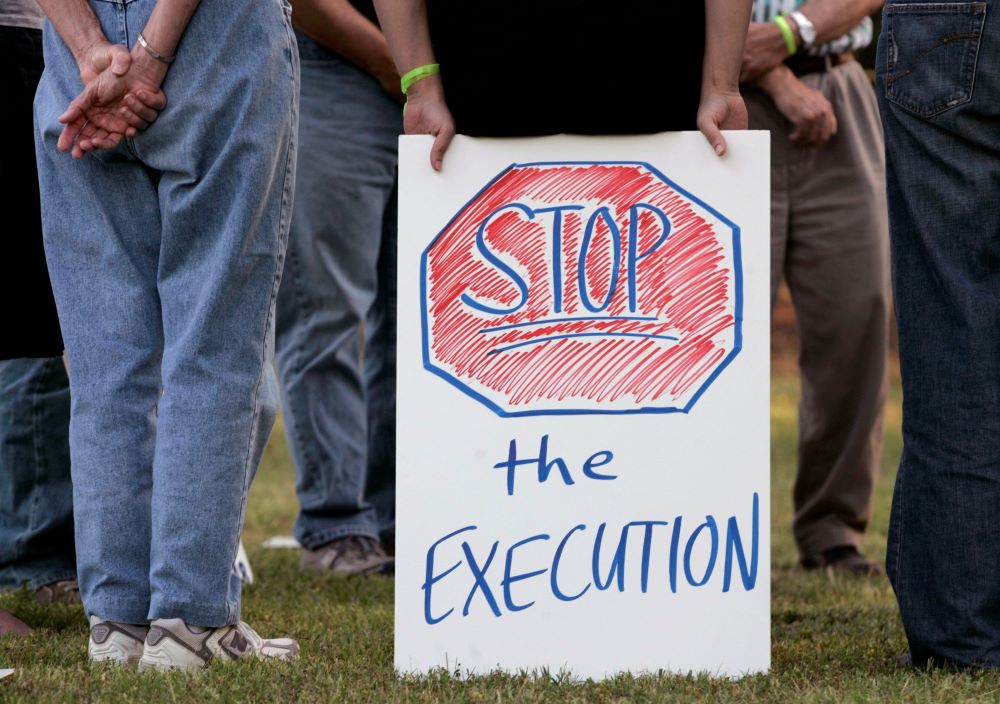 Hands are shown holding a sign that reads, "Stop the Execution."