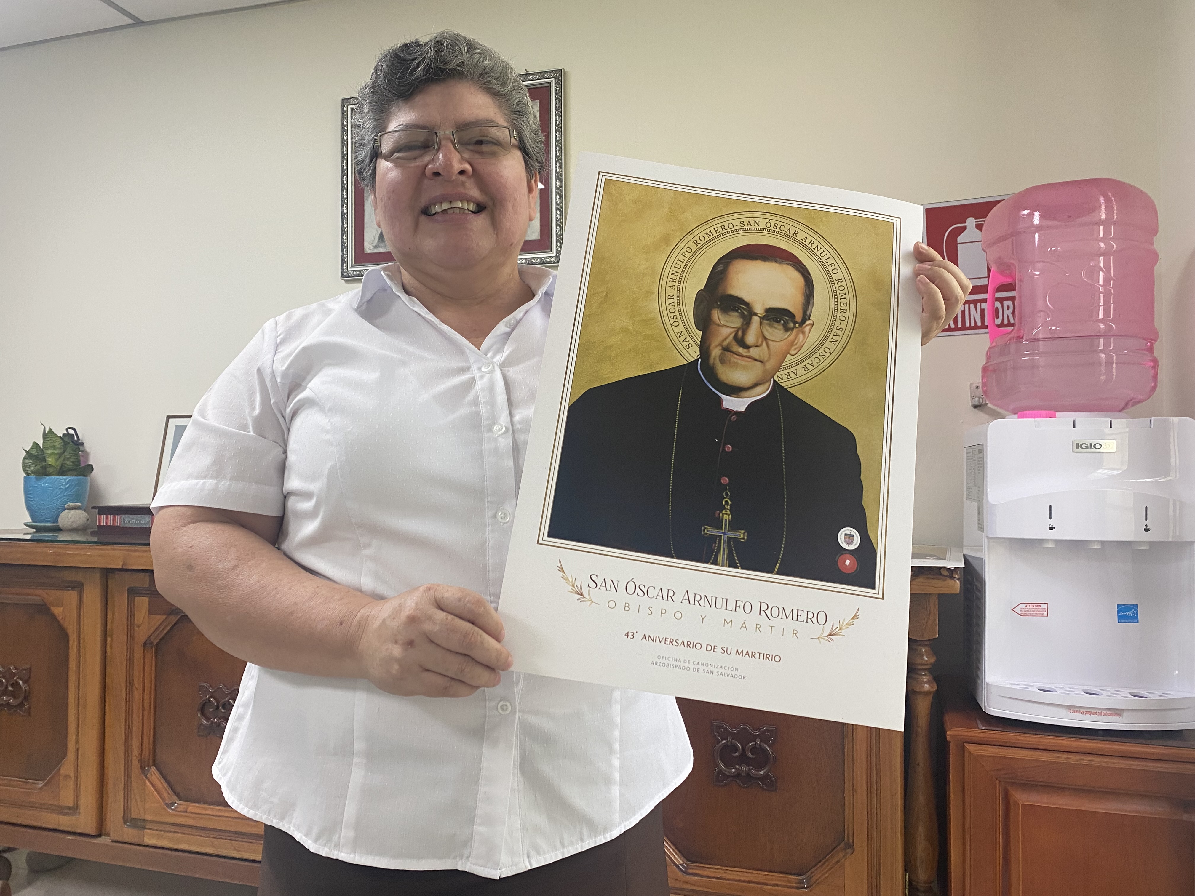 La Hna. Tránsito de la Cruz Valdez Crespín sostiene un póster de san Óscar Romero el 24 de marzo, en su oficina cercana a la capilla donde fue martirizado.