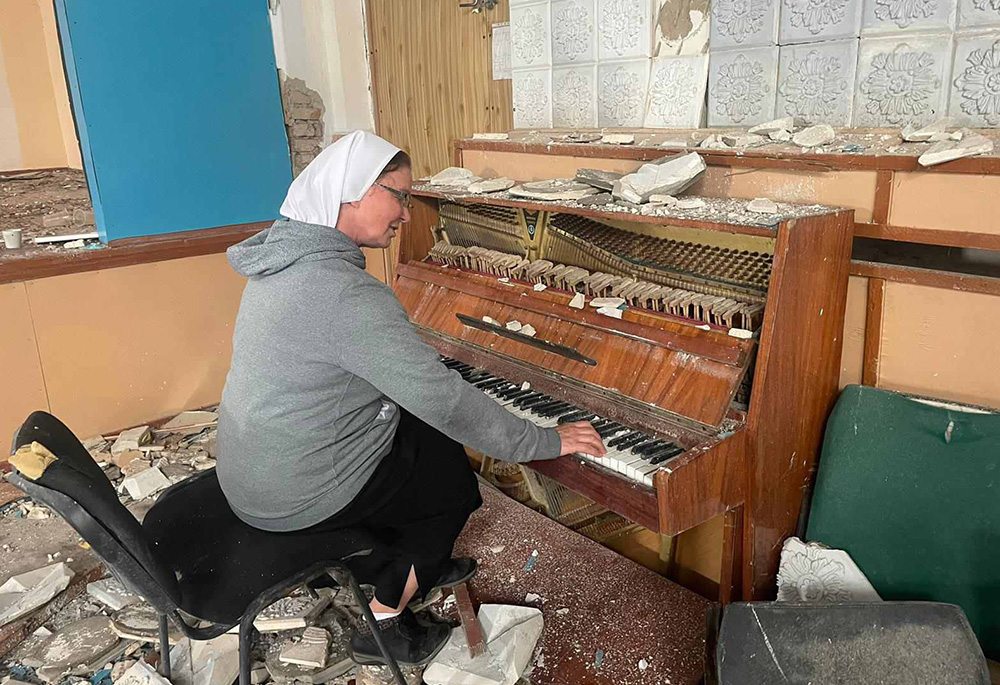 Sr. Lydia Timkova sits down at a piano in destroyed property in a village near Mykolaiv, eastern Ukraine. (Courtesy of Lydia Timkova)