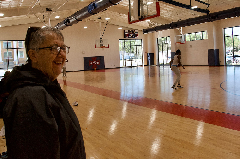 Sr. Mary Agnes Cashman watches young men play basketball in the Edmundite Missions recreation center March 15 in Selma, Alabama.