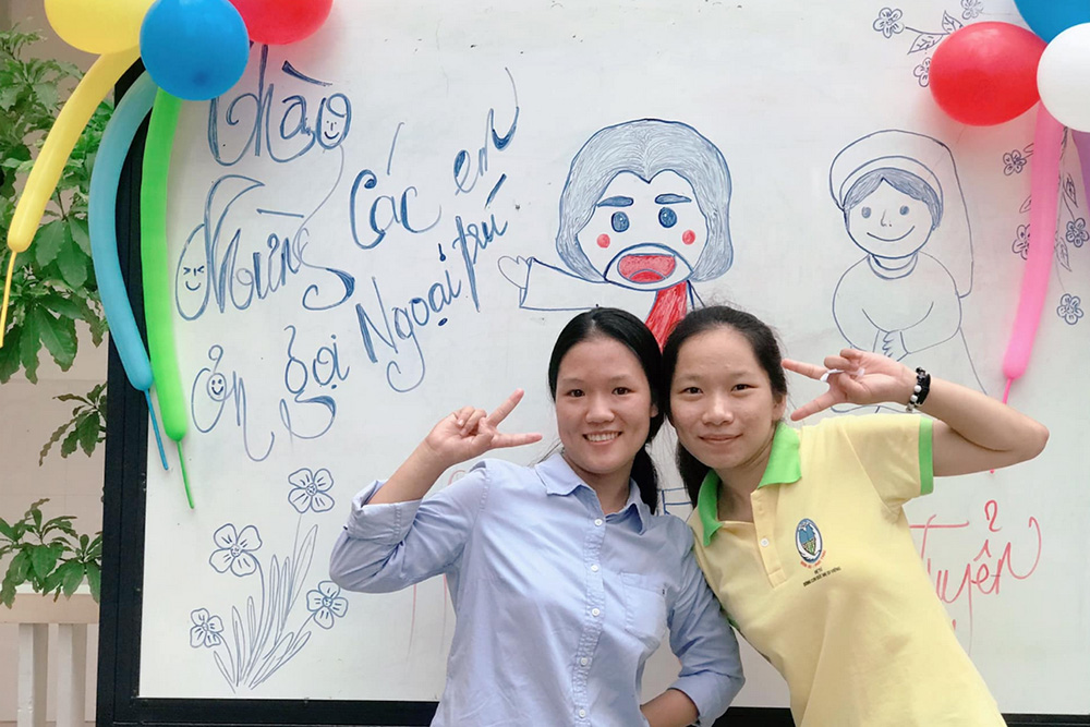 Srs. Mary Truong Thi Sen, left, and Anna Nguyen Thi Nhung pose for a photo before a banner, welcoming vocation candidates to the Daughters of Our Lady of the Visitation's headquarters in Hue, Vietnam, April 23. They plan to hold another vocation gathering on May 7. 