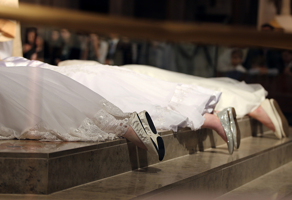 Three women consecrated as virgins lie prostrate during a 2017 ceremony. Pope Francis praised consecrated virgins June 1, 2020, the 50th anniversary of St. Paul VI's revival of the "Ritual for the Consecration of Virgins." (CNS/Joel Breidenbach)