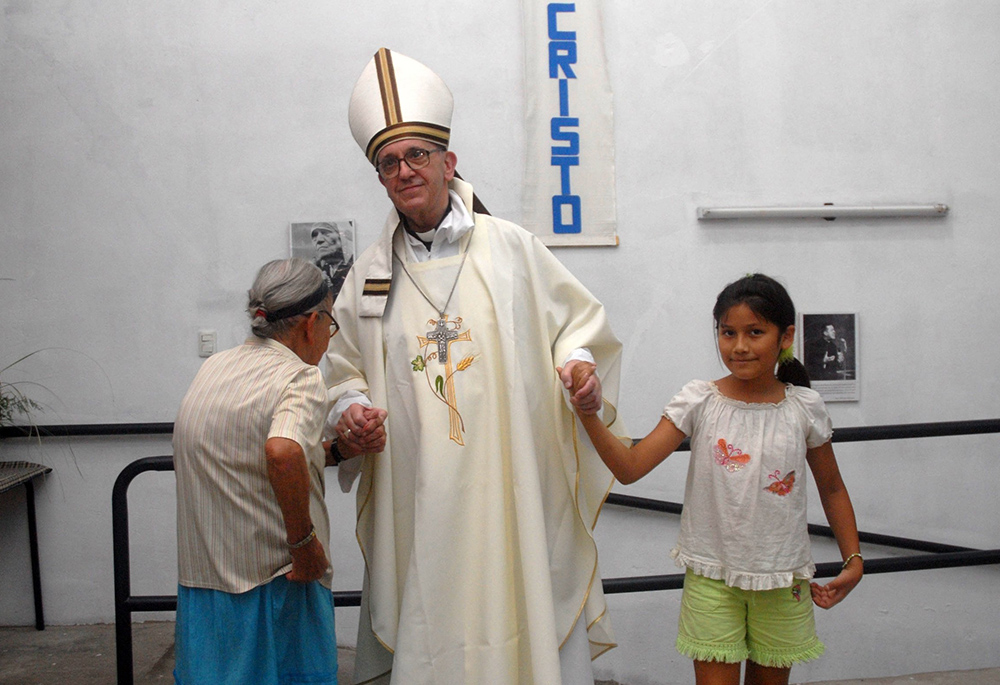 Argentine Cardinal Jorge Mario Bergoglio holds the hands of a woman and girl during Holy Thursday Mass in 2008 at a church in a poor section of Buenos Aires, Argentina. Bergoglio was later elected pope March 13, 2013, becoming the first pope to take the name of St. Francis of Assisi. (CNS/Reuters/Enrique Garcia Medina)