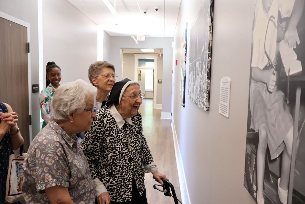 Ursuline Sisters of Louisville, from left, Barbara Bir, Loretta Guenther and Rita Dressman look at a hallway plaque honoring the sisters June 2 at St. Joseph Children's Home. Caitlyn Green, a member of St. Joseph’s advancement team, looks on. The Ursuline Sisters served children at the home from 1897 to 2010. (Courtesy of Ursuline Sisters of Louisville/Kathy Williams)