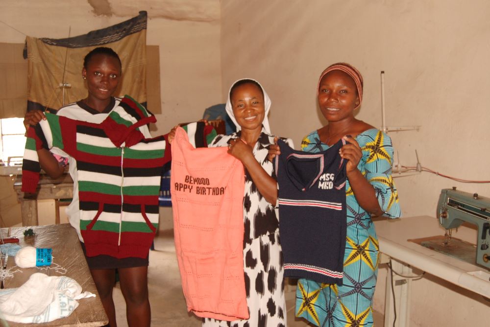 Sr. Lydia Agba and students at the Women’s Empowerment Center display clothes they knitted. (GSR photo/Valentine Benjamin)
