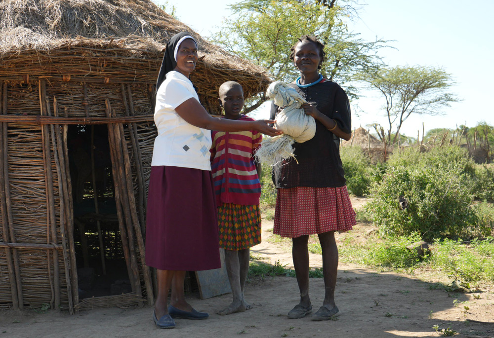 Sr. Jannifer Hiuhu hands over food rations to Chepokoronto Lotingora, a 33-year-old mother of eight. After a fire destroyed Lotingora's former home and claimed two of her children, the Incarnate Word Sisters helped her rebuild her home and provided her with food to sustain her family. (GSR photo/Wycliff Peter Oundo)