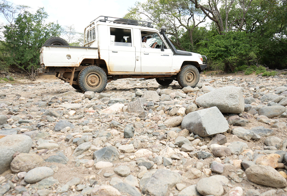 Sr. Jannifer Hiuhu navigates her truck over a dry riverbed on her journey from Rotu village to the town of Chemolingot in Baringo County, 68 kilometers (about 42 miles) away. She makes this perilous run every three weeks to collect food aid and essentials for her congregation, crossing dry riverbeds and rocky bush roads through the East Pokot hills, which is known for being a haven for bandits. (GSR photo/Wycliff Peter Oundo)