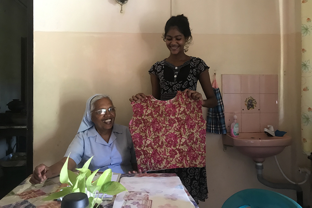 Danisha Ravihansi, right, shows her first tailoring product to Sr. Rani Fernando. The Salvatorian sisters teach embroidery, stitching and tailoring to children in Don Boscopura, Negombo, Sri Lanka. (Thomas Scaria)