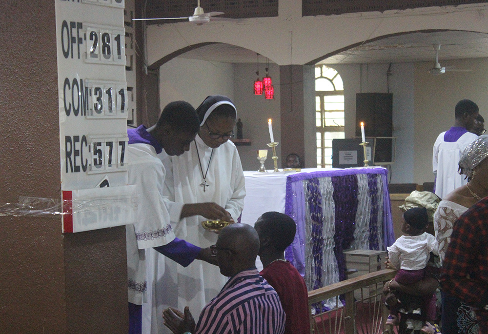 Sr. Justina Nnajiofor helps to give holy Communion to parishioners during Mass March 5 at Our Lady of Fatima Catholic Church in Gusau, Zamfara state. (Patrick Egwu)