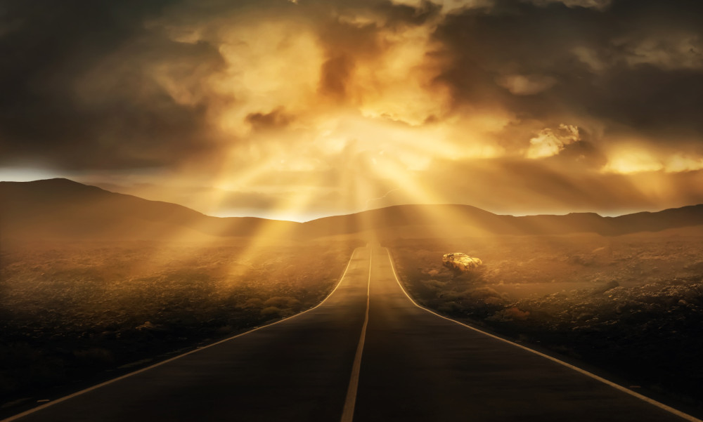 The sun peeking through the clouds shining on a highway (Pixabay/Dorothe)
