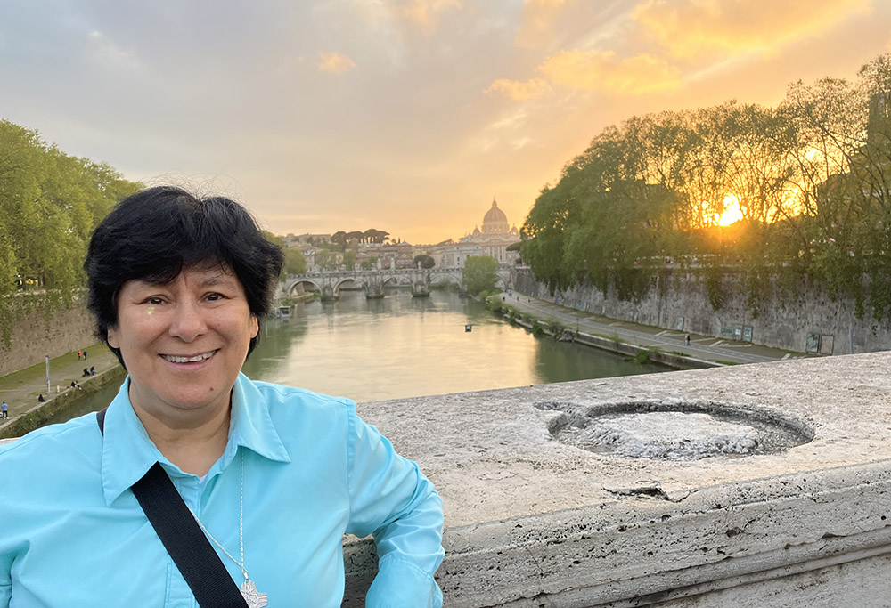 Sr. María Elena Méndez Ochoa stands on a Tiber River bridge in Rome. In the background is St. Peter's Basilica and a beautiful sunset. (Gabriela Ramirez)