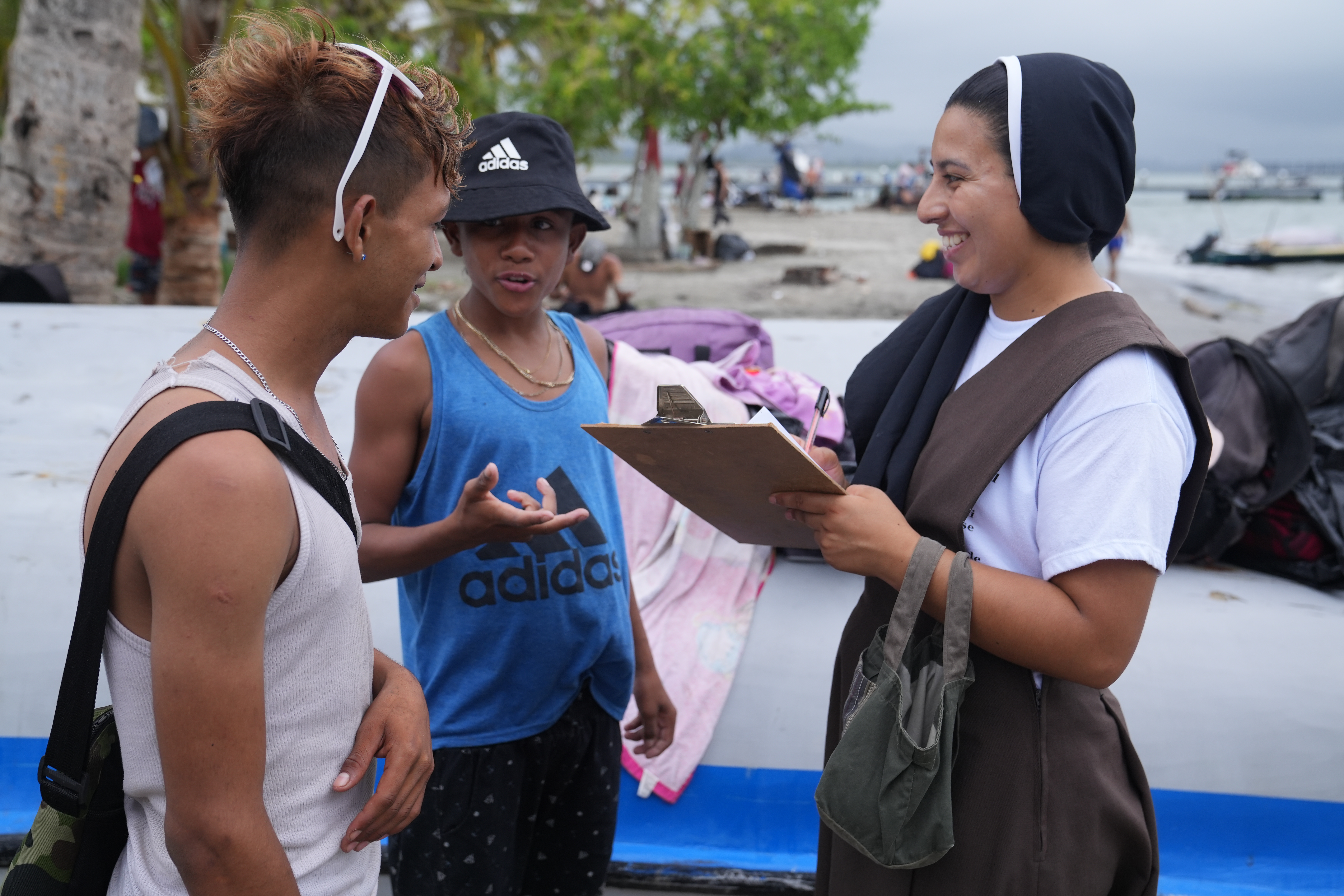 Una hermana franciscana habla con dos jóvenes migrantes, dos chamos venezolanos, que se encontraban en la playa de Necoclí, Colombia, el 28 de abril. Todas las mañanas, las hermanas recorren la playa para repartir tiques de comida a los migrantes y proporcionarles información sobre los servicios locales. (Foto: GSR/Manuel Rueda)