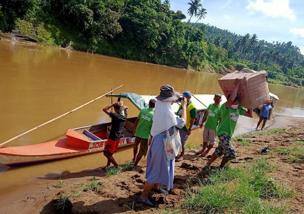 Sr. Amadea Donadilla, St. Scholastica's Hospital administrator, guides men bringing the goods for distribution to Ginulgan, one of the communities by the riverside, where the sisters minister. (Courtesy of Edita Eslopor)