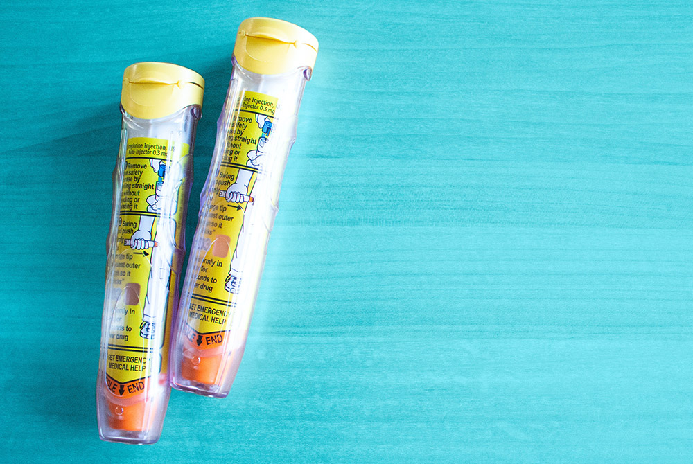 Two epipens on a painted blue surface (Unsplash/Pixielumina Photography)