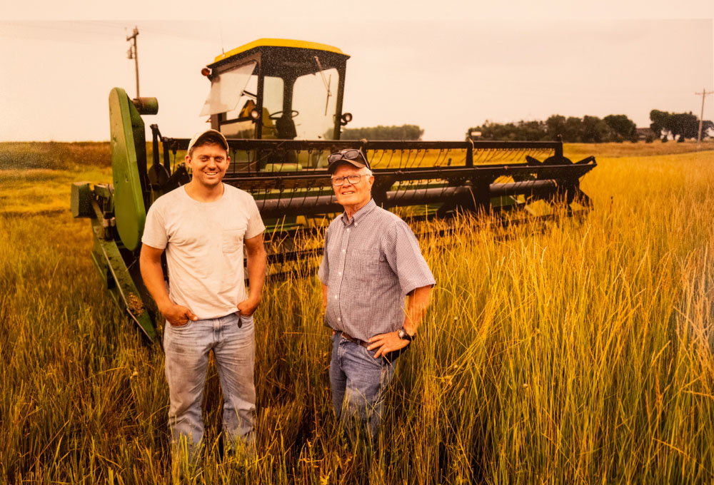 Luke Peterson and Carmen Fernholz in a Kernza field, with their gleaner ready to harvest the summer crop (Photo by Dodd Demas for Friends of the Mississippi River)