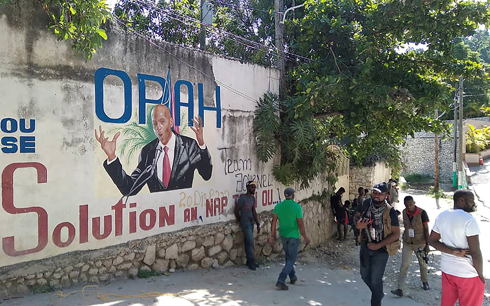 People walk past a wall with a mural depicting Haitian President Jovenel Moïse July 7, 2021, in Port-au-Prince. Moïse was assassinated in an attack in the early hours of July 7 at his home outside of the capital, Port-au-Prince, the prime minister said. (CNS/Reuters/Robenson Sanon)