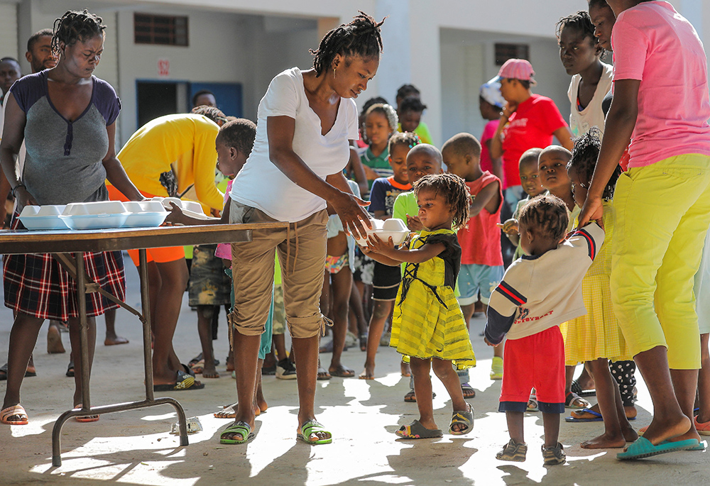 Haitian children who escaped violence in Cité Soleil line up to receive food at a school in Port-au-Prince July 22, 2022. An upsurge in gang-related violence has shut access to health services across some urban areas in Haiti, leaving one in 20 children living in Cité Soleil, a violence-ravaged commune, at risk of dying from severe acute malnutrition, UNICEF warned. (CNS/Reuters/Ralph Tedy Erol)