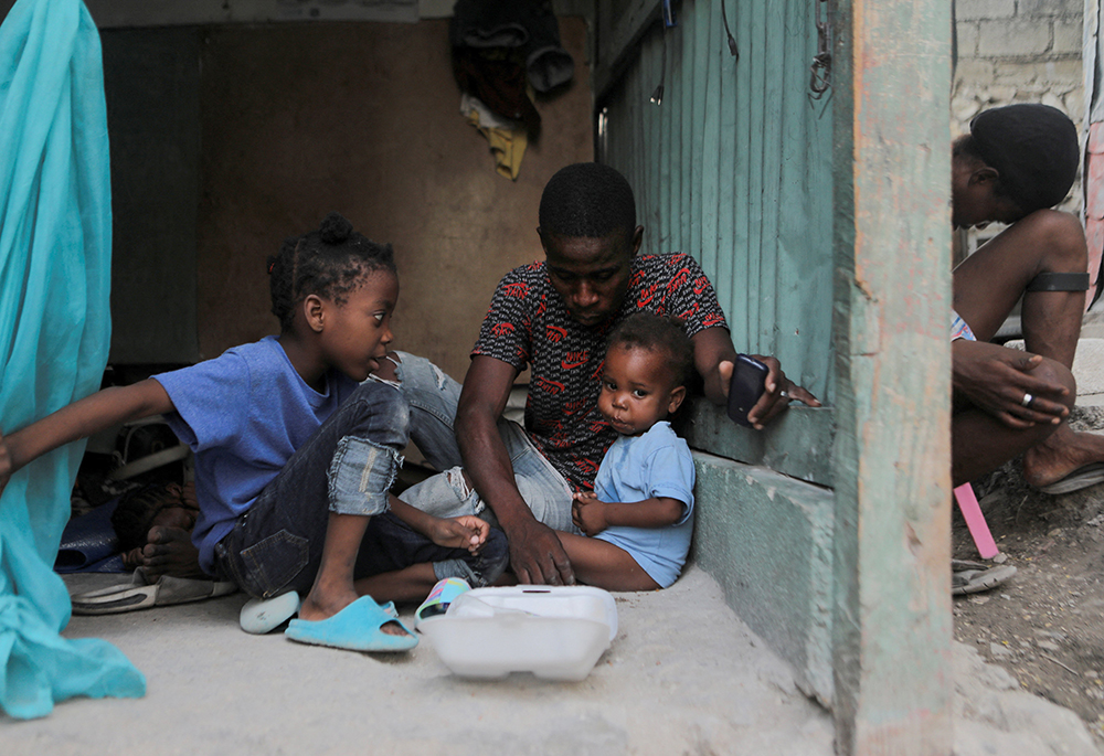 A family shares a meal at the New Church of God of Deliverance camp for displaced people, June 19 in Port-au-Prince, Haiti. The camp now harbors 120 families from various hard-hit neighborhoods since gangs have expanded their turf and now control communities where some 2 million people live. (OSV News/Reuters/Ralph Tedy Erol)
