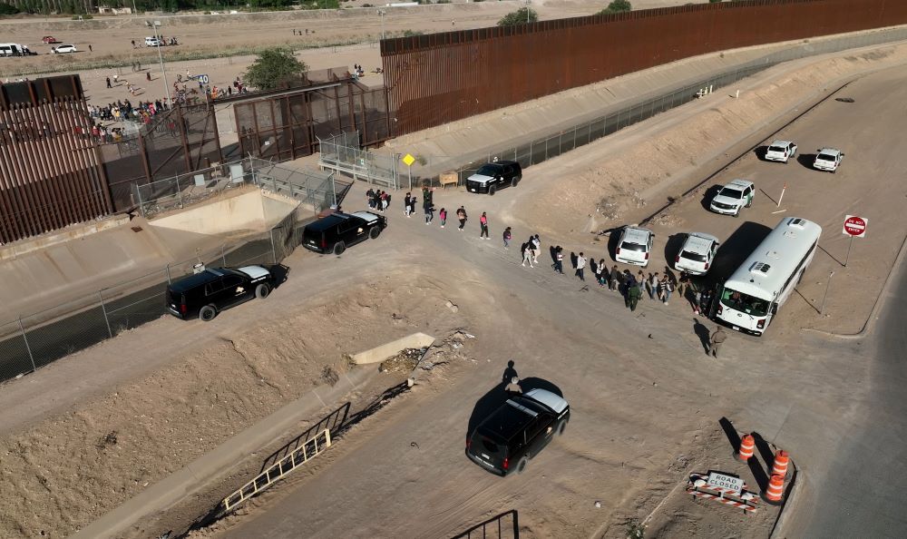 Migrants line up to board a U.S. Customs and Border Protection bus after crossing the U.S.-Mexico border before the lifting of Title 42 near El Paso, Texas, May 11. (OSV News/Reuters/Julio Cesar Chavez)