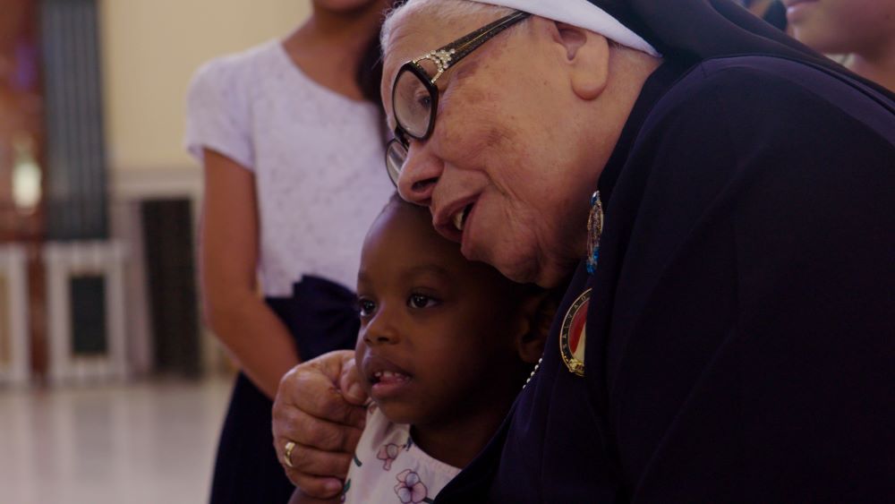 Sr. Maria Rosa Leggol hugs a child in this scene from the film "With This Light," premiering in select theaters this summer.