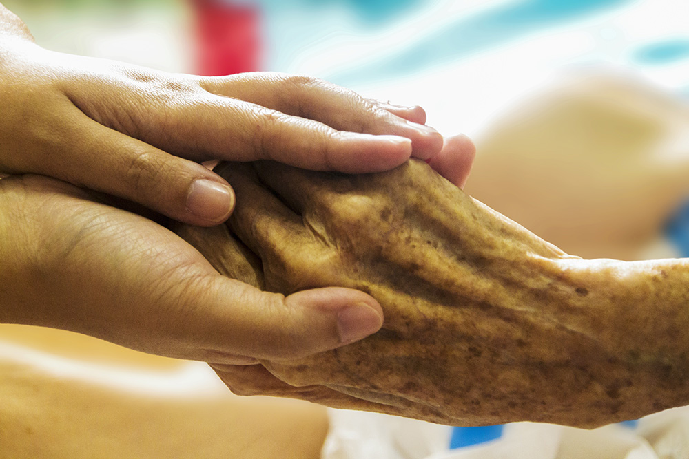 A younger person's hands hold the hand of an elderly person (Pixabay/truthseeker08)