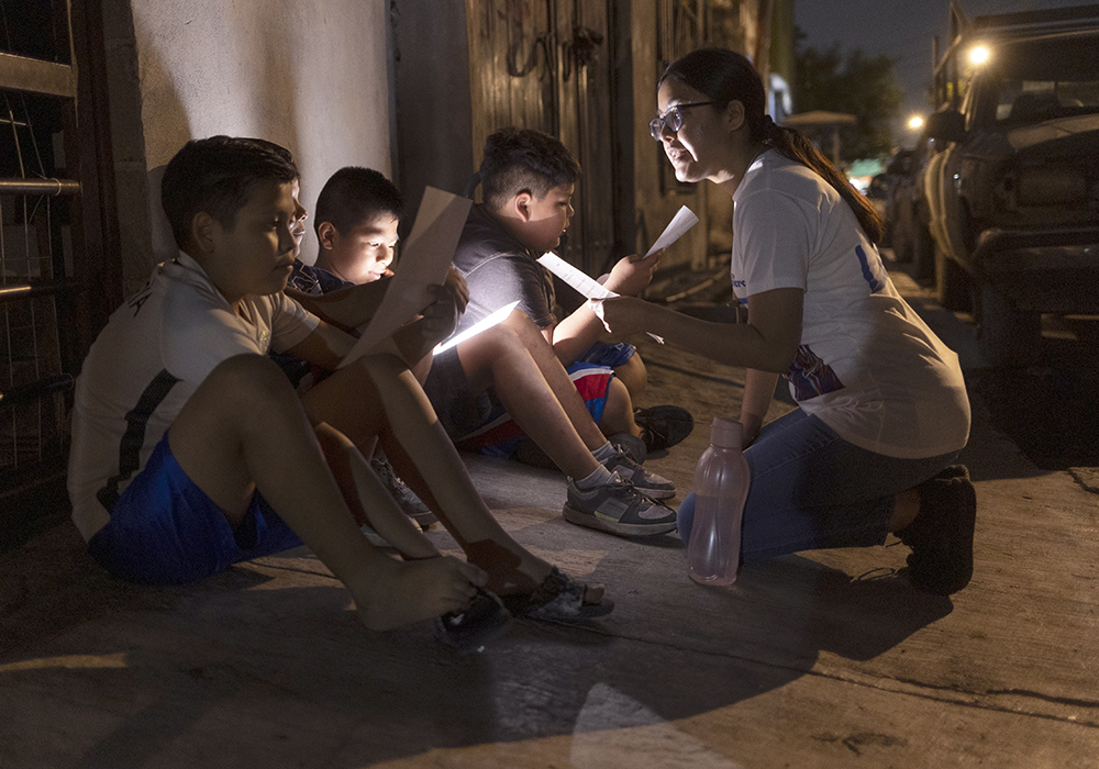 Lay missionary Josseline Montes Jiménez, right, teaches religious acclamations to members of Los Monckis, during a visit to their hangout in Monterrey, Mexico, in May. (Nuri Vallbona)