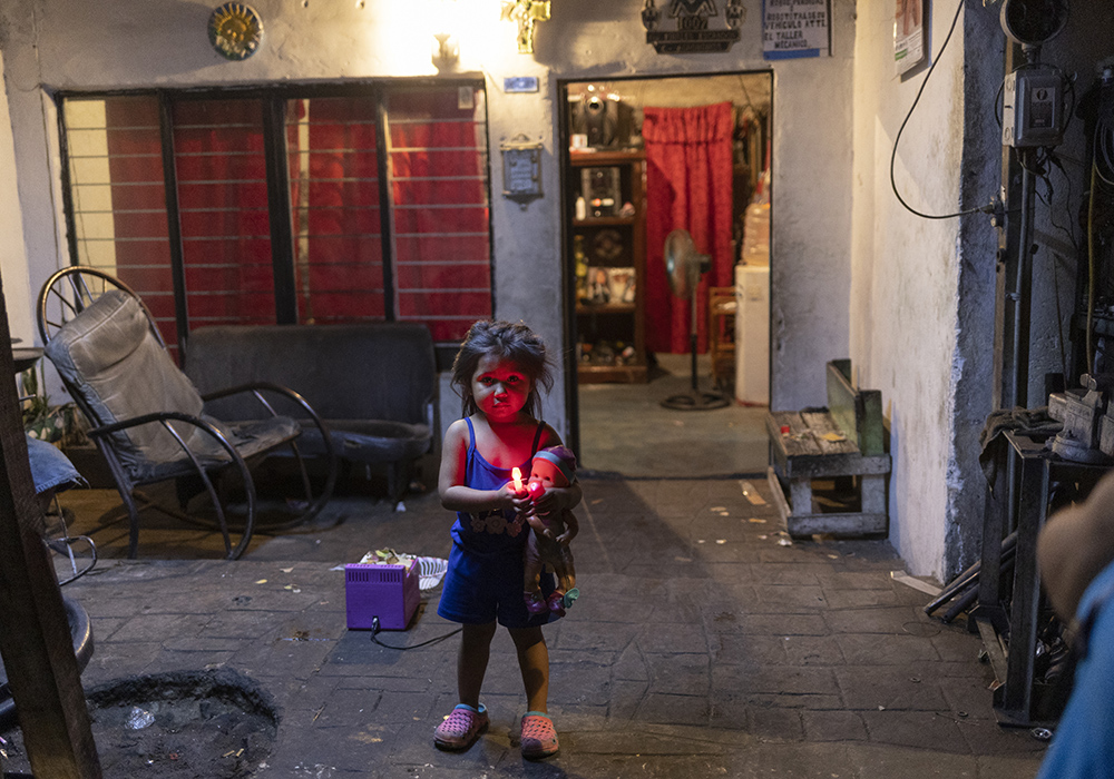 Dana, 3, watches the sisters and missionaries talk with Los Monckis youth gang members during their visit in Monterrey, Mexico. (Nuri Vallbona)