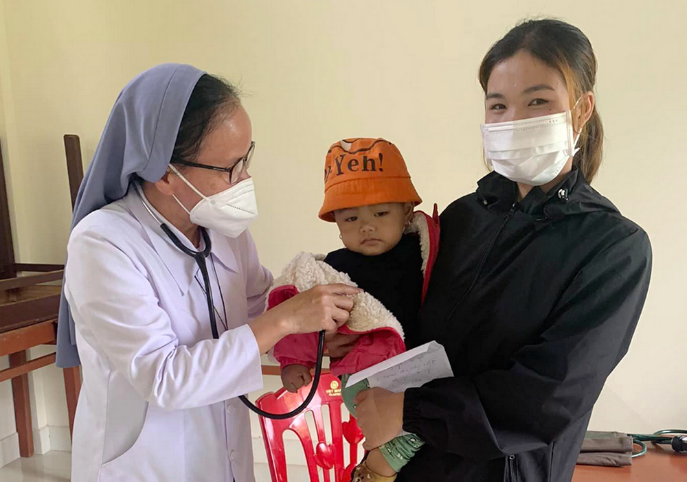Filles de Marie Immaculée Sr. Rosa Vo Thi Hien examines the baby of Van Kieu ethnic Ho Thi Xoa May 26 in Cam Lo district, Vietnam. (GSR photo/Joachim Pham)