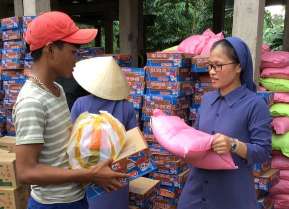 Lovers of the Holy Cross of Hue Sr. Lucia Nguyen Dieu Trinh (right) gives rice, instant noodles, and other food to a patient in Huong Hoa district April 25. (GSR photo/Joachim Pham)