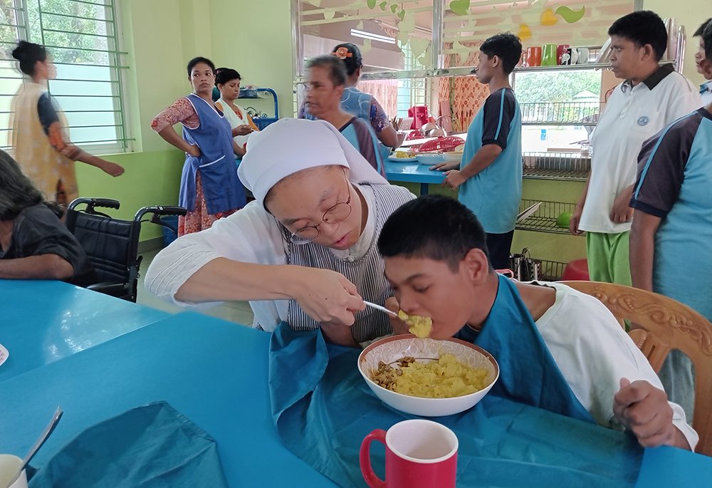 Sr. Matthew Lee feeds a person with a disability. (Sumon Corraya)