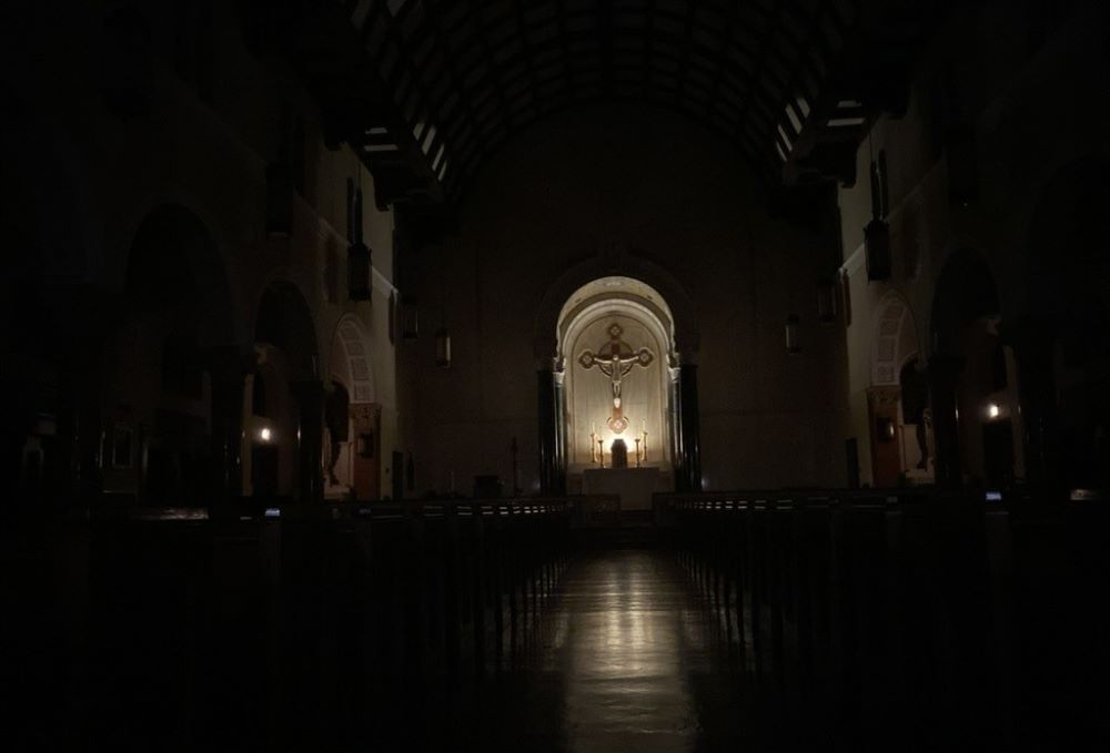 a dark empty church w/ light on the sanctuary