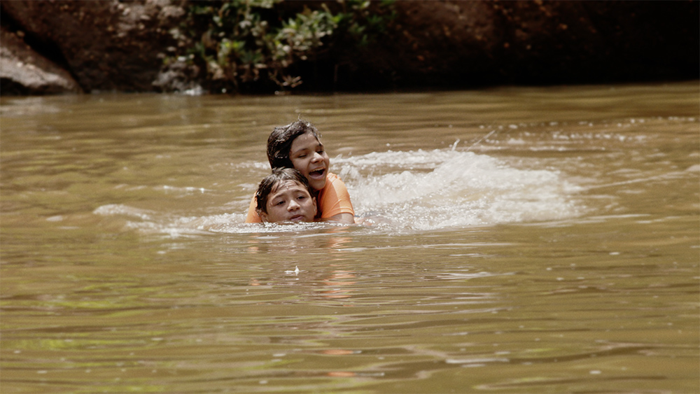 Honduran teenager María swims with her brother in the documentary film "With This Light." (Courtesy of Miraflores Films)