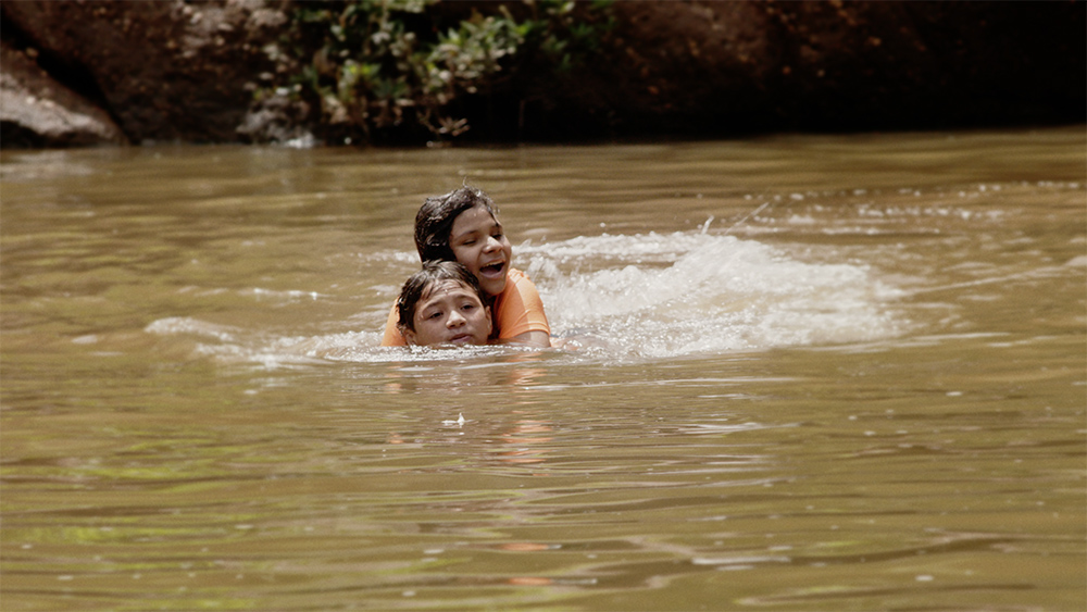 La adolescente hondureña María nada con su hermano en la película documental With This Light. (Foto: cortesía de Miraflores Films)