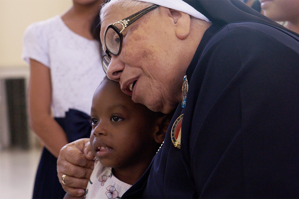 Sr. María Rosa Legoll of the School Sisters of St. Francis hugs a child in the documentary film "With This Light." (Courtesy of Miraflores Films)