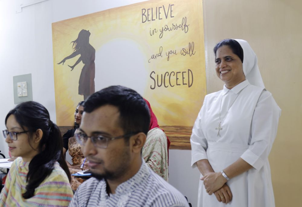 Nun dressed in white stands near a poster that says, "Believe in yourself and you will succeed."