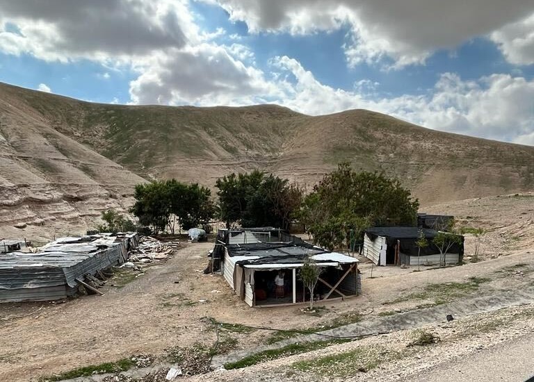 several simple buildings stand together in the desert.