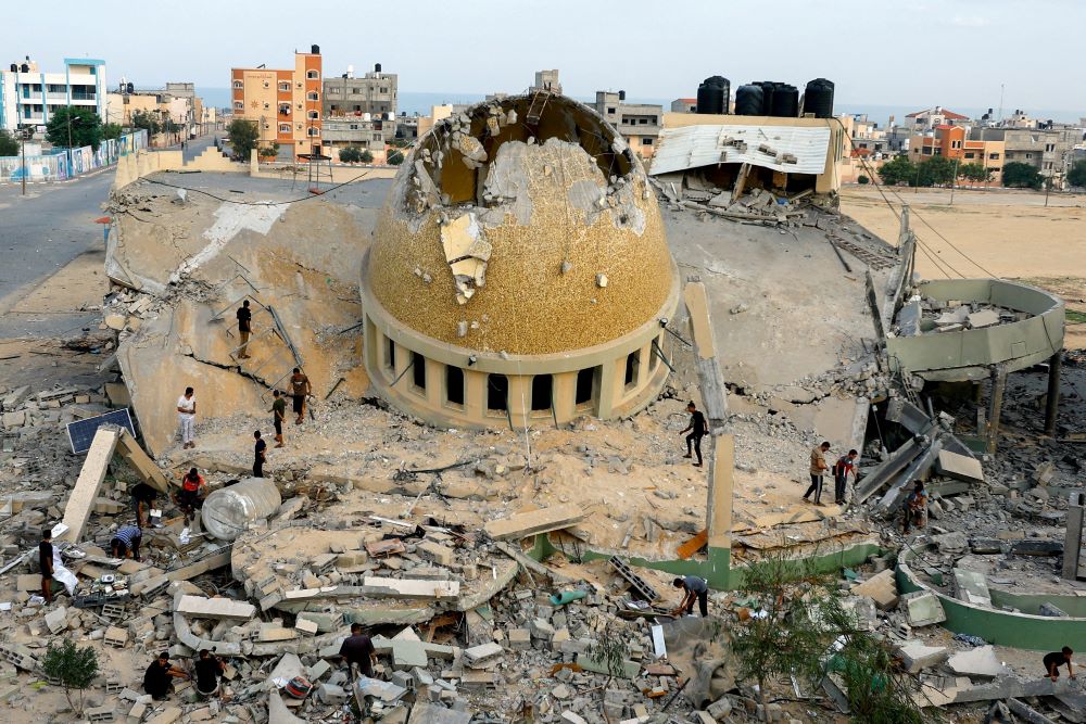 People look at the rubble of a mosque.