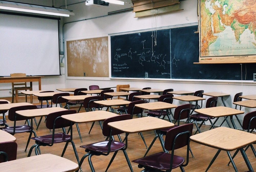 Blackboard and big map are visible in an empty classroom.