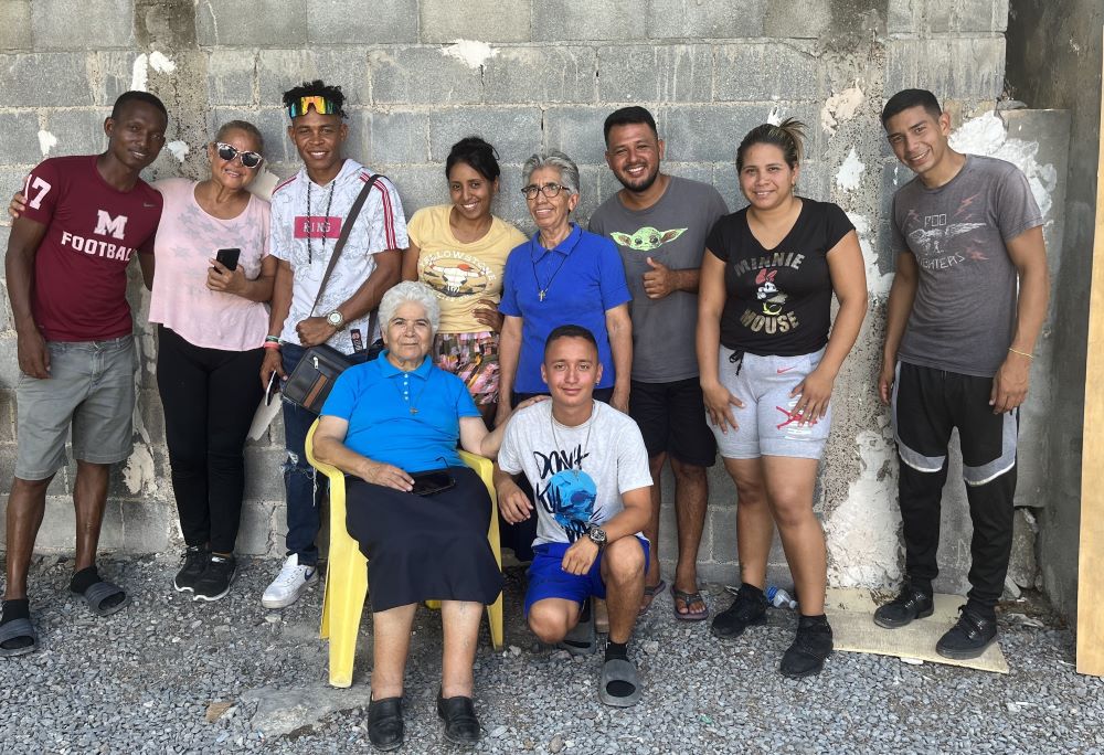 5. Sr. María de la Luz González Díaz, sitting, and Sr. Obdulia Guerrero Jiménez, standing, appear with a migrant group from many Latin American countries in the convent's garden.