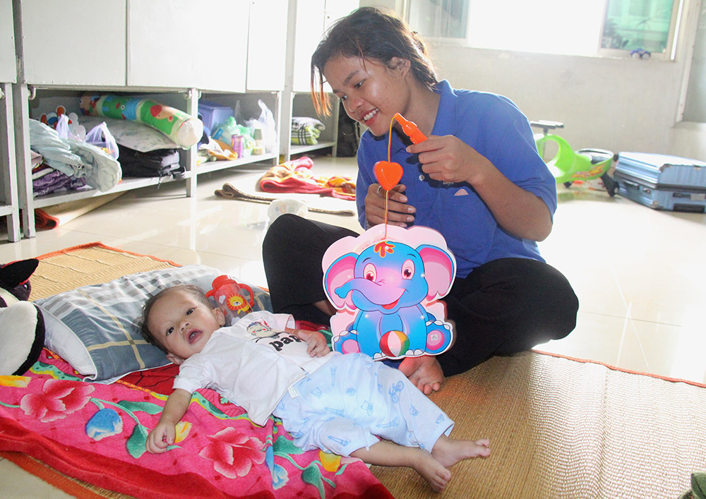 Mary Rolan Hin, an 18-year-old from Kon Tum province in Vietnam's Central Highlands, and her 9-month-old son play with a lantern Sept. 30 at the home for heart patients in Ho Chi Minh City. Her son, who has congenital heart disease, is preparing for medical checkups at a public hospital in the city. (GSR photo/Joachim Pham)