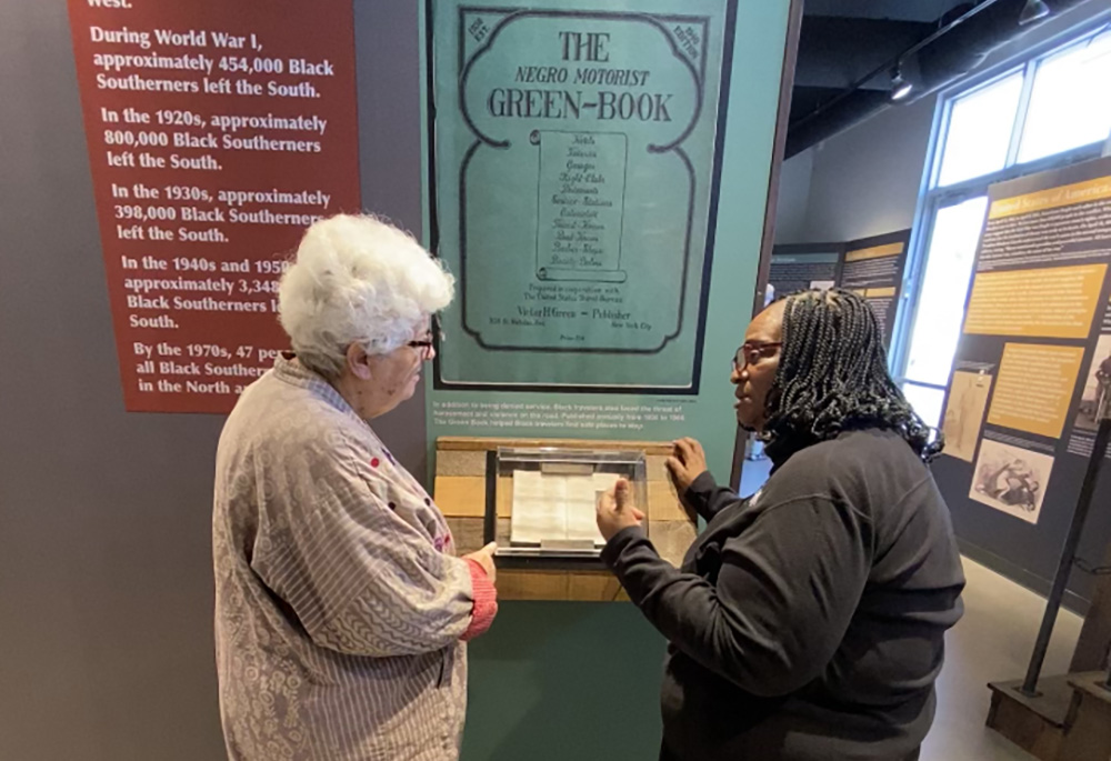 Sr. Barbara Pfarr (left), a School Sister of Notre Dame, visits America's Black Holocaust Museum in Milwaukee on Sept. 29. She listens to docent Brenda Jackson explain that in the 1930 edition of the Green Book, only two cities in Wisconsin, Fond du Lac and Oshkosh, offered services to the Black community. (Courtesy of Barbara Pfarr)